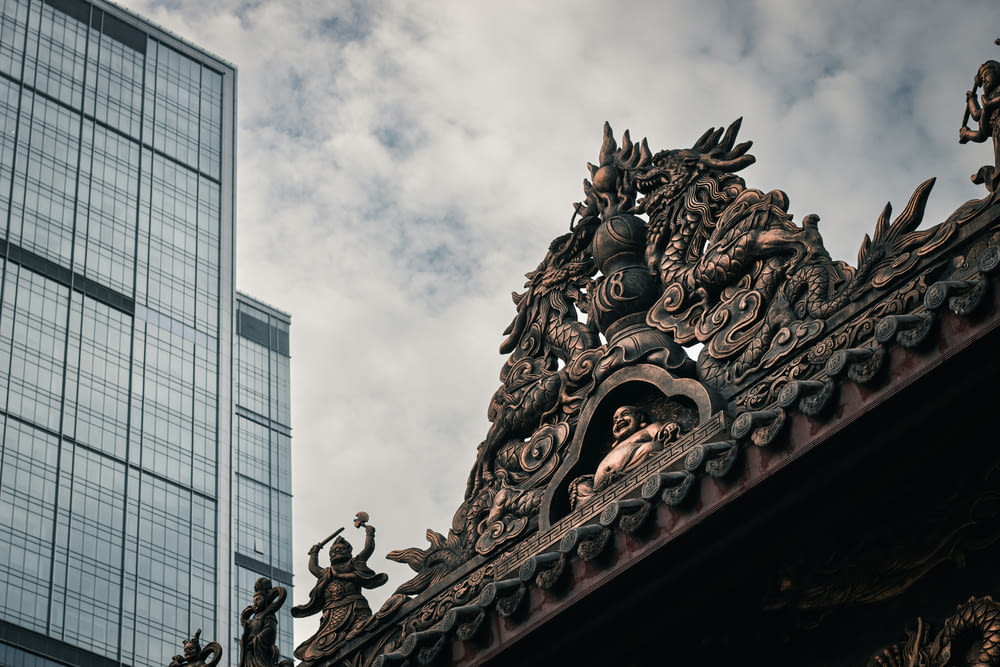 a building with a statue on top of it next to a tall building