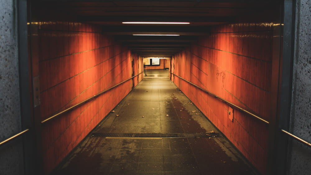 a long hallway with red walls and a light at the end