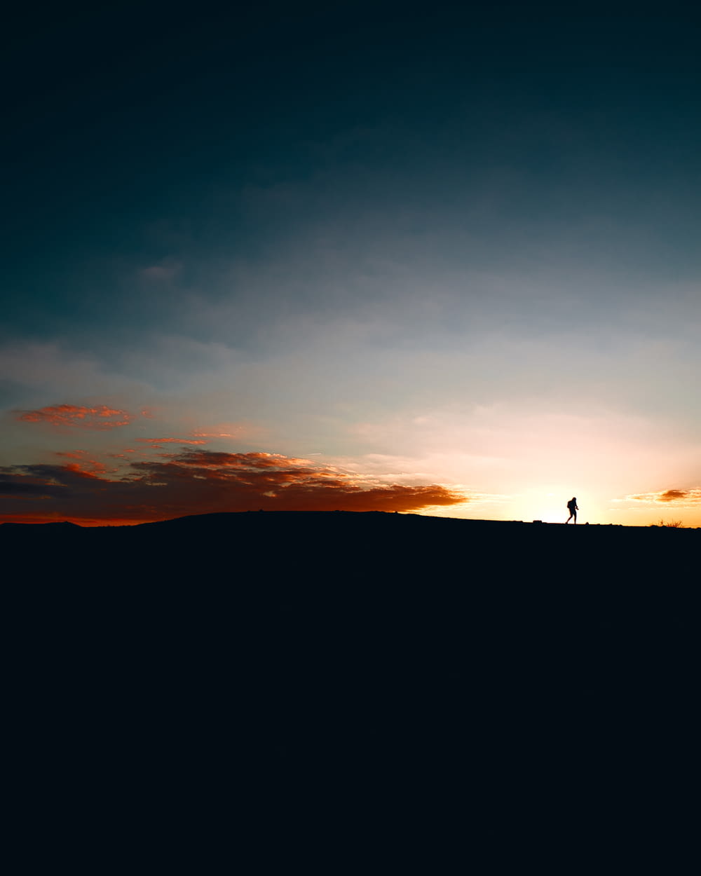 a person standing on top of a hill at sunset