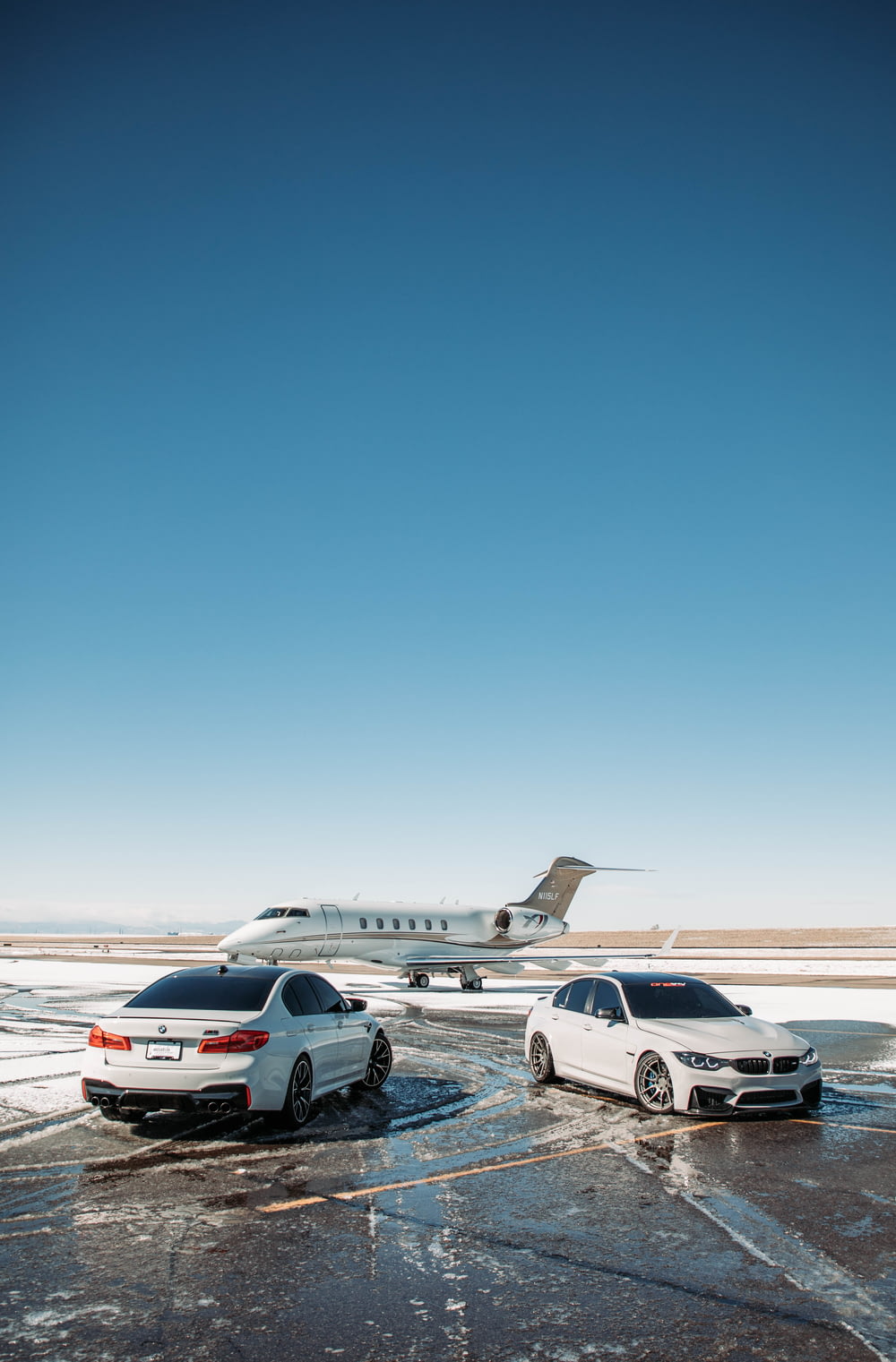 two cars parked in a parking lot next to an airplane