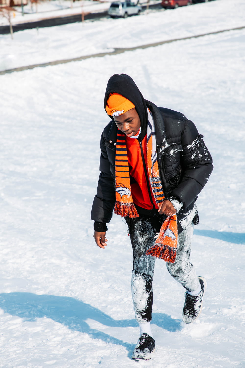 a young boy in a black jacket and orange scarf snowboarding