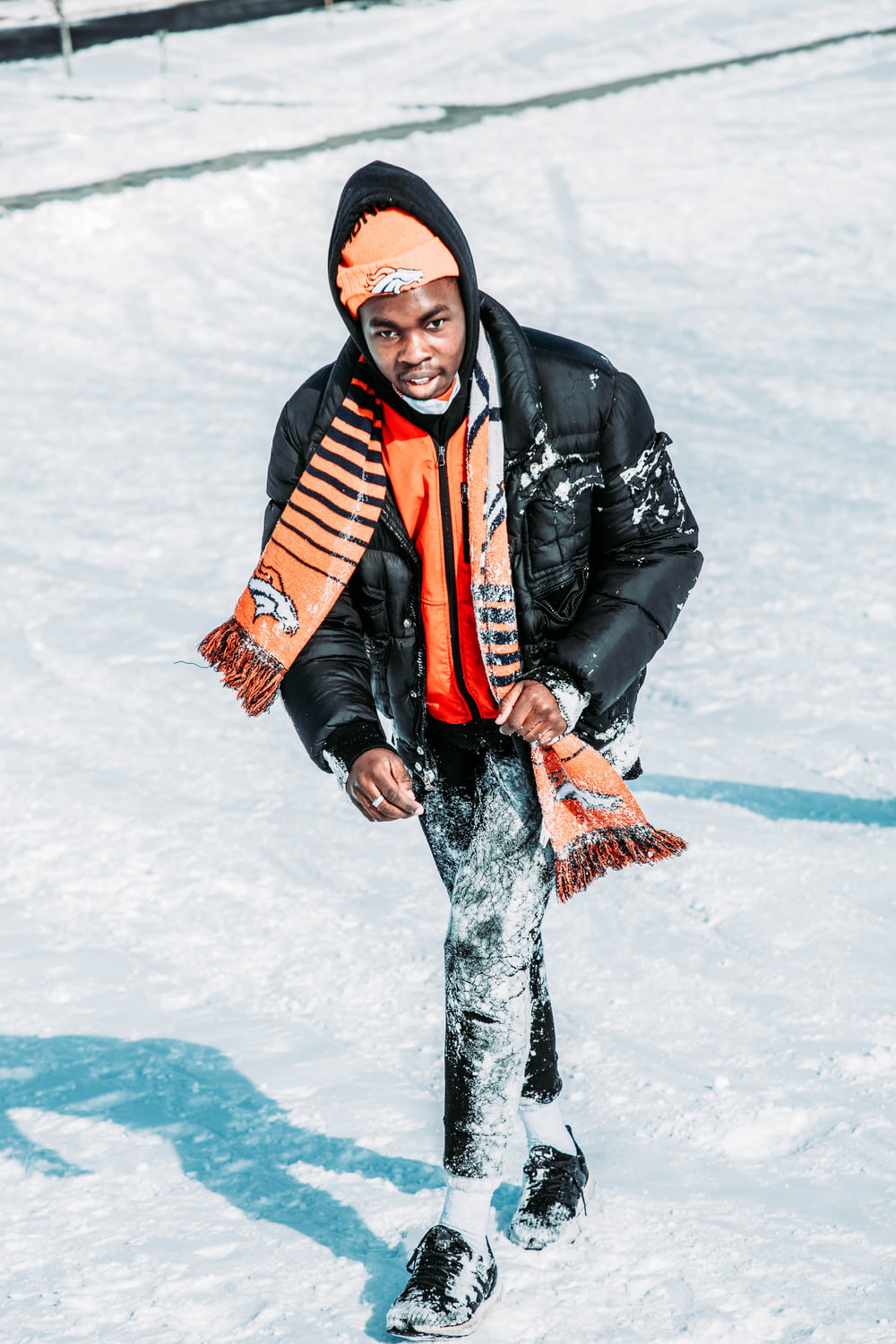 a man standing in the snow with a scarf around his neck