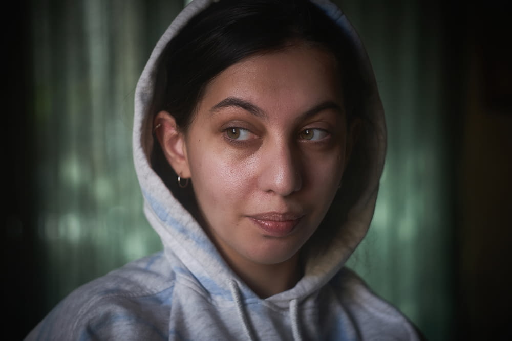 a woman in a hooded sweatshirt looking at the camera