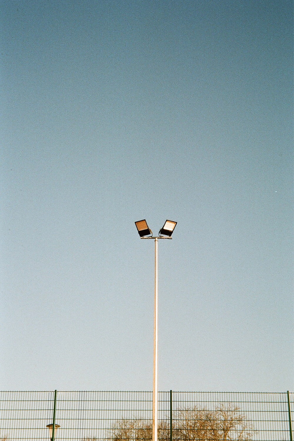 a couple of street lights sitting next to a fence