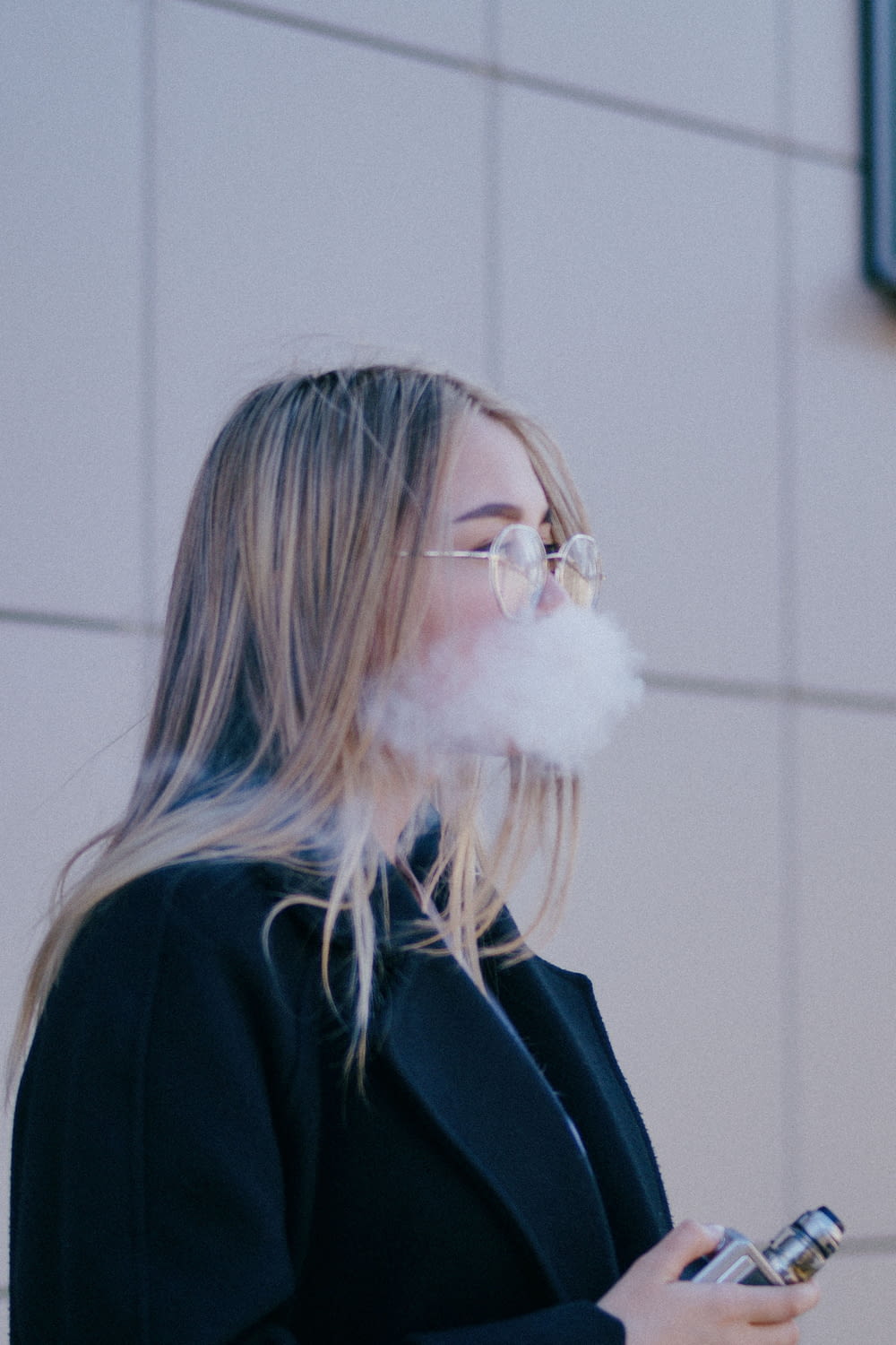 a woman smoking a cloud of smoke while holding a cell phone