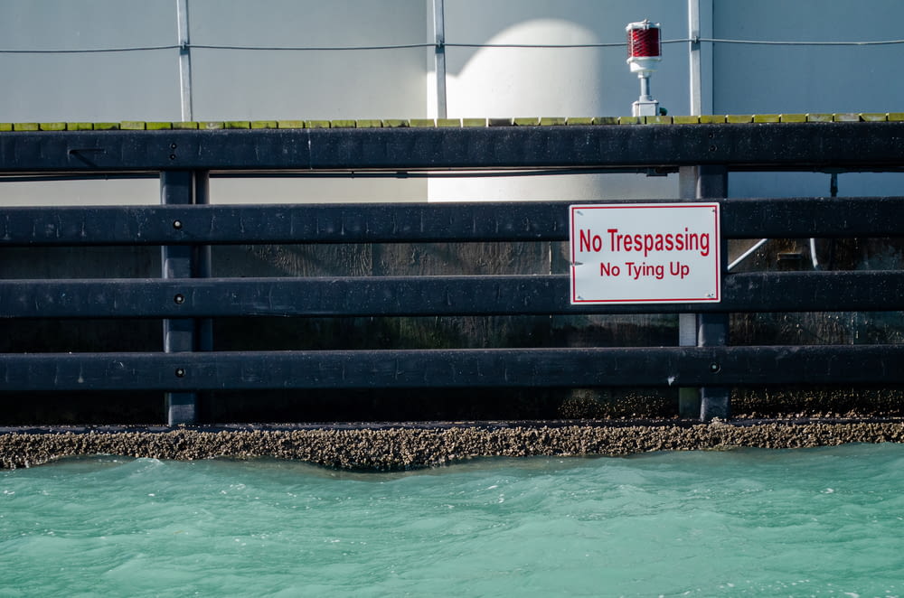 a no trespassing sign on a bridge over a body of water