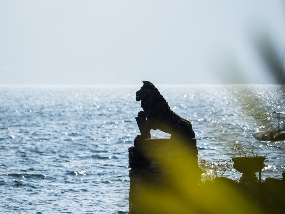 Una statua di un leone seduto sulla cima di una roccia vicino all'oceano