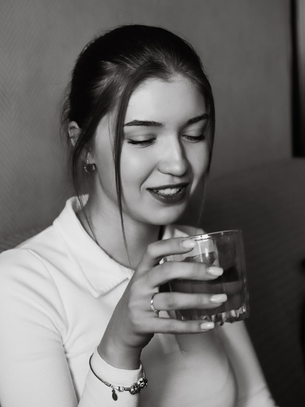 a black and white photo of a woman holding a glass of water