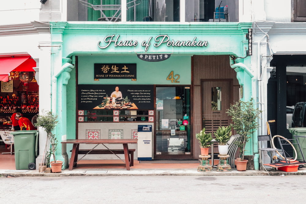 a store front with a green awning and a wooden bench in front of it
