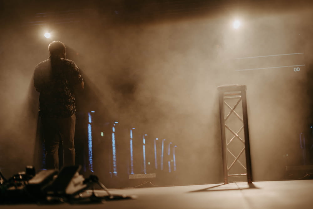 um homem em pé na frente de um palco com neblina