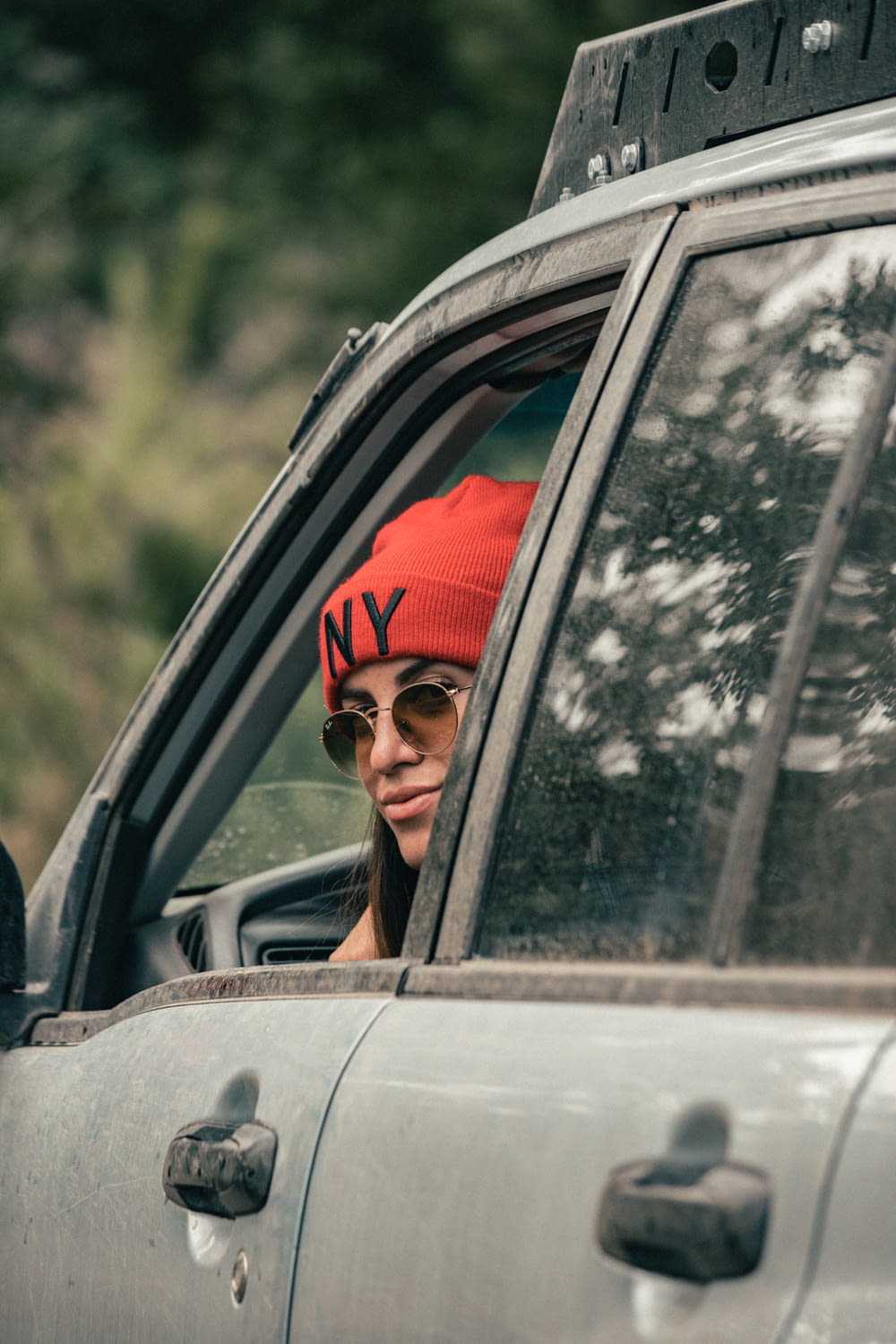 赤い帽子をかぶり、サングラスをかけた女性が車に座っている