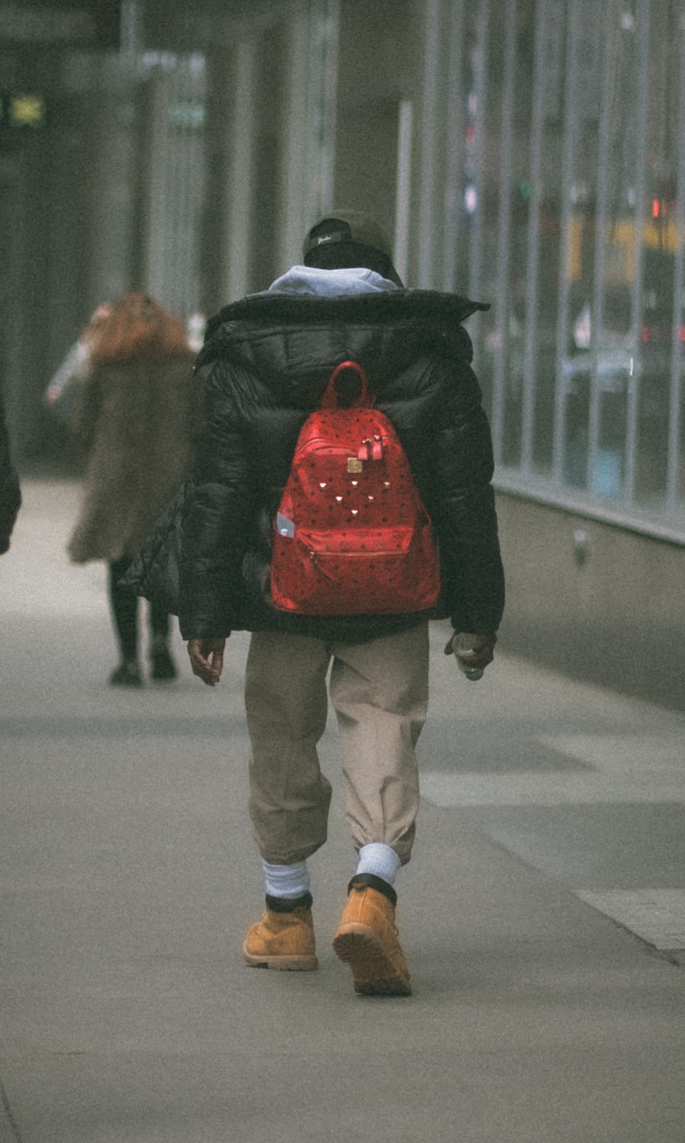 a person walking down a sidewalk with a red backpack