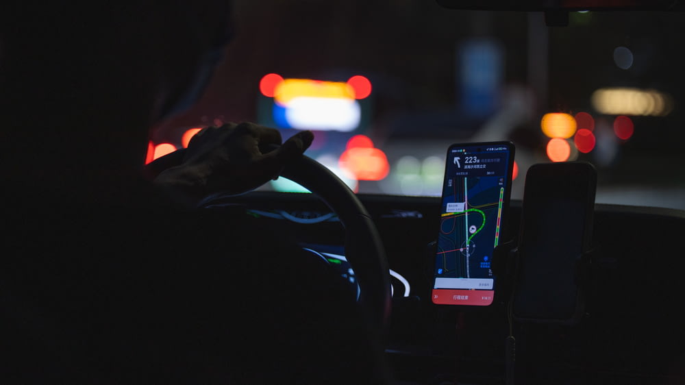a person driving a car at night with a cell phone
