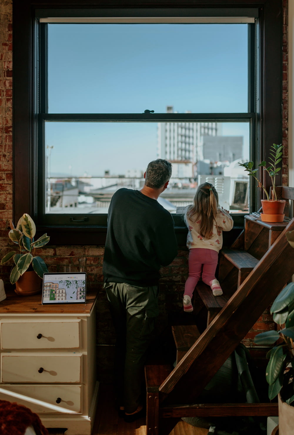 Un uomo e una bambina guardano fuori da una finestra