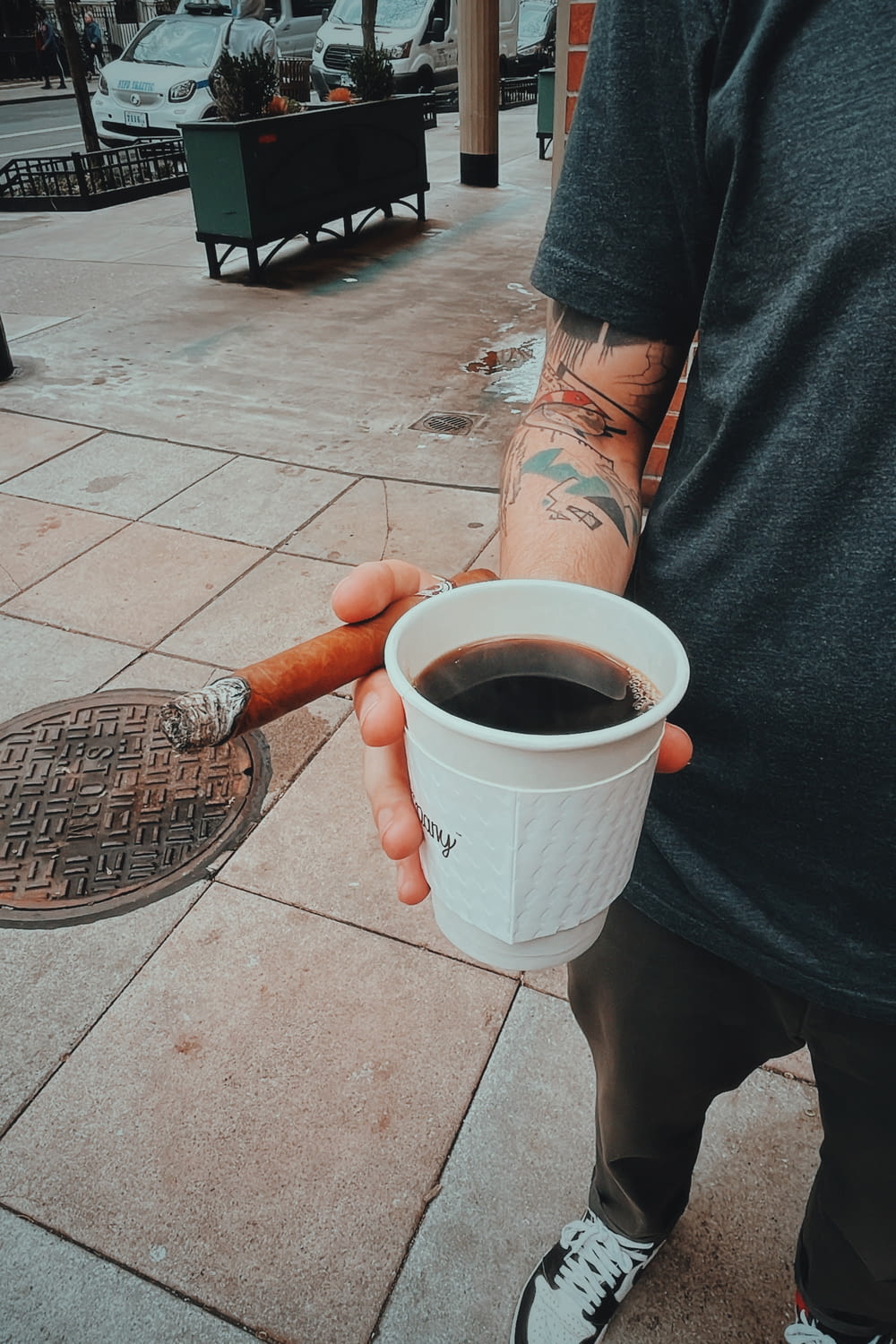 a man holding a cup of coffee and a cigarette