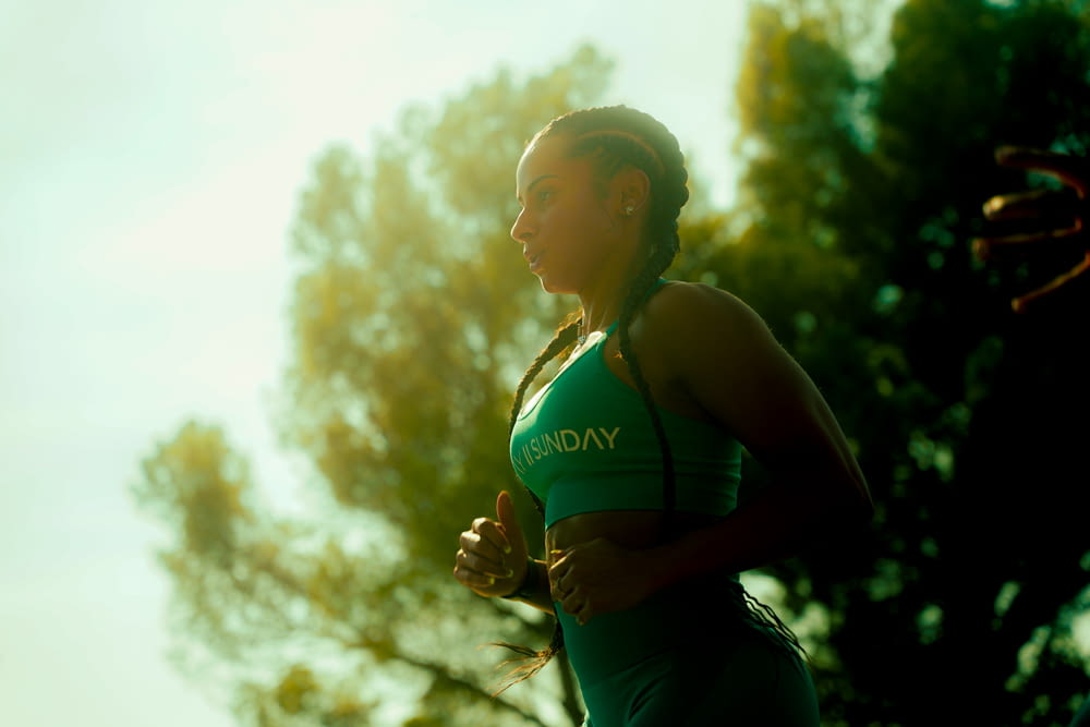 a woman in a green top running in the sun