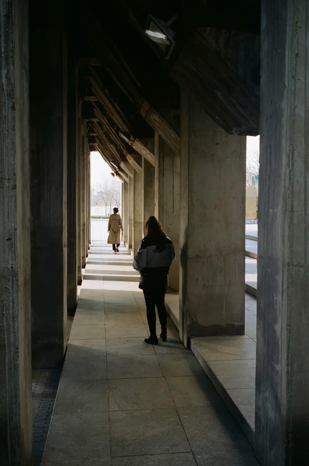 a woman is walking down a long hallway