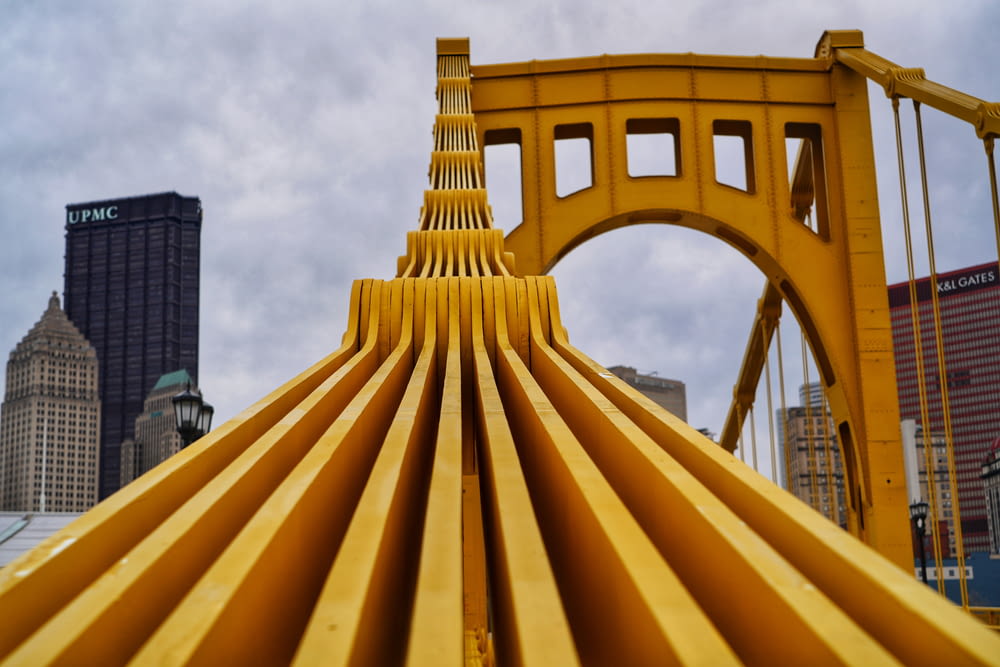 a close up of a yellow structure with a city in the background
