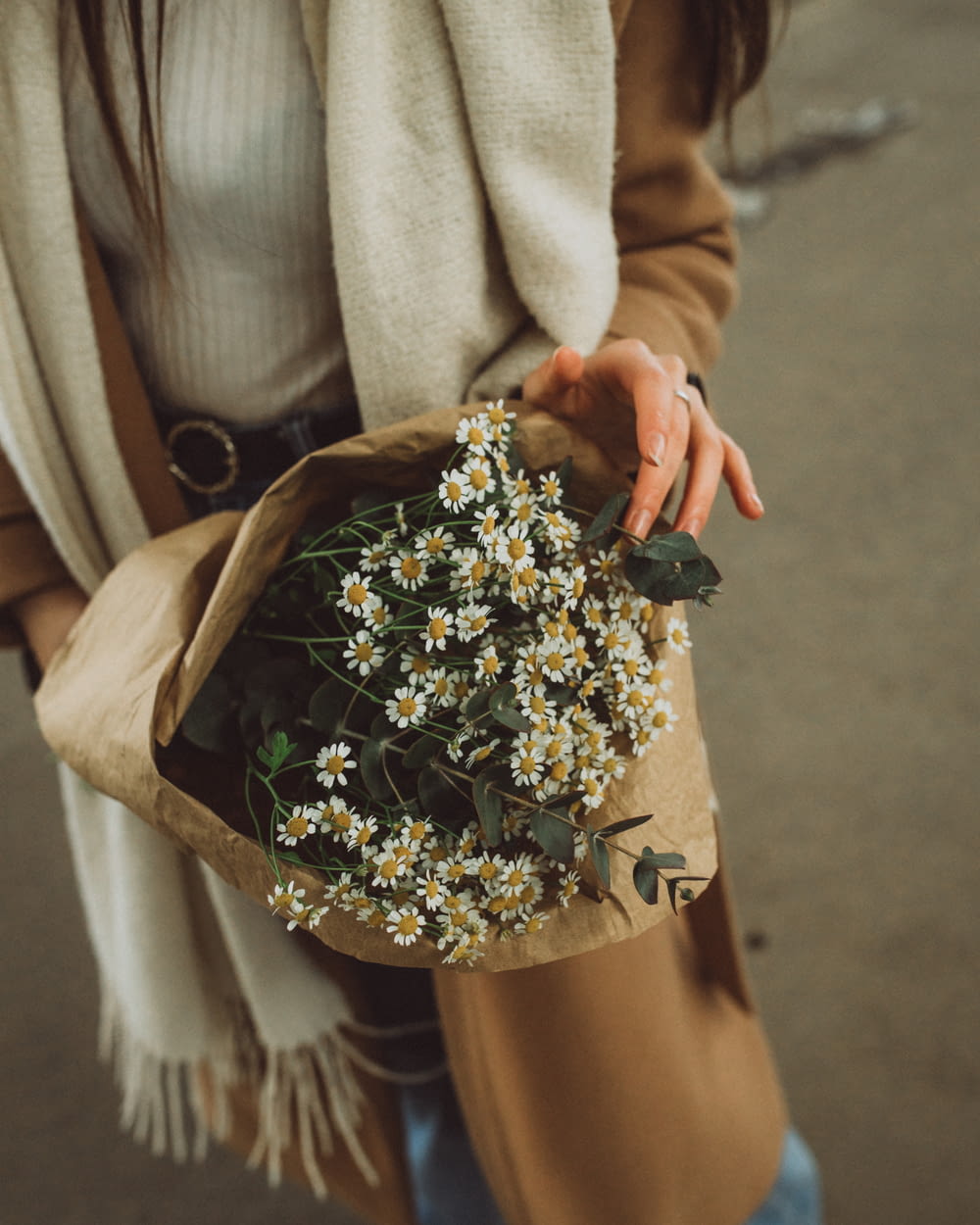 a woman is holding a bouquet of daisies