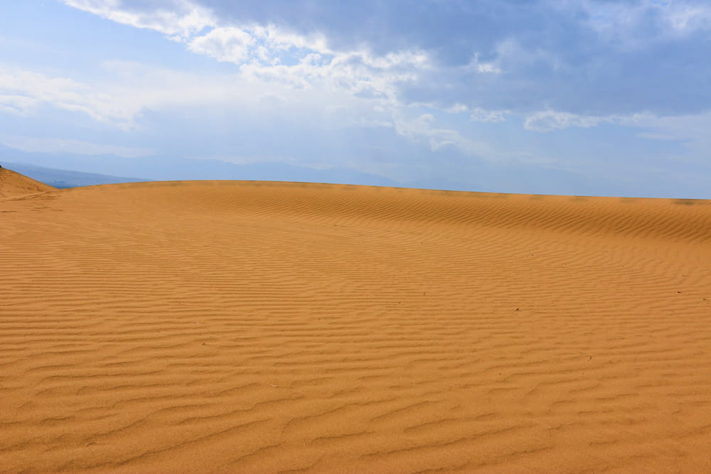 a large sand dune with a blue sky in the background