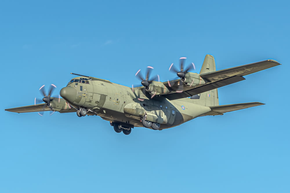 a large military plane flying through a blue sky