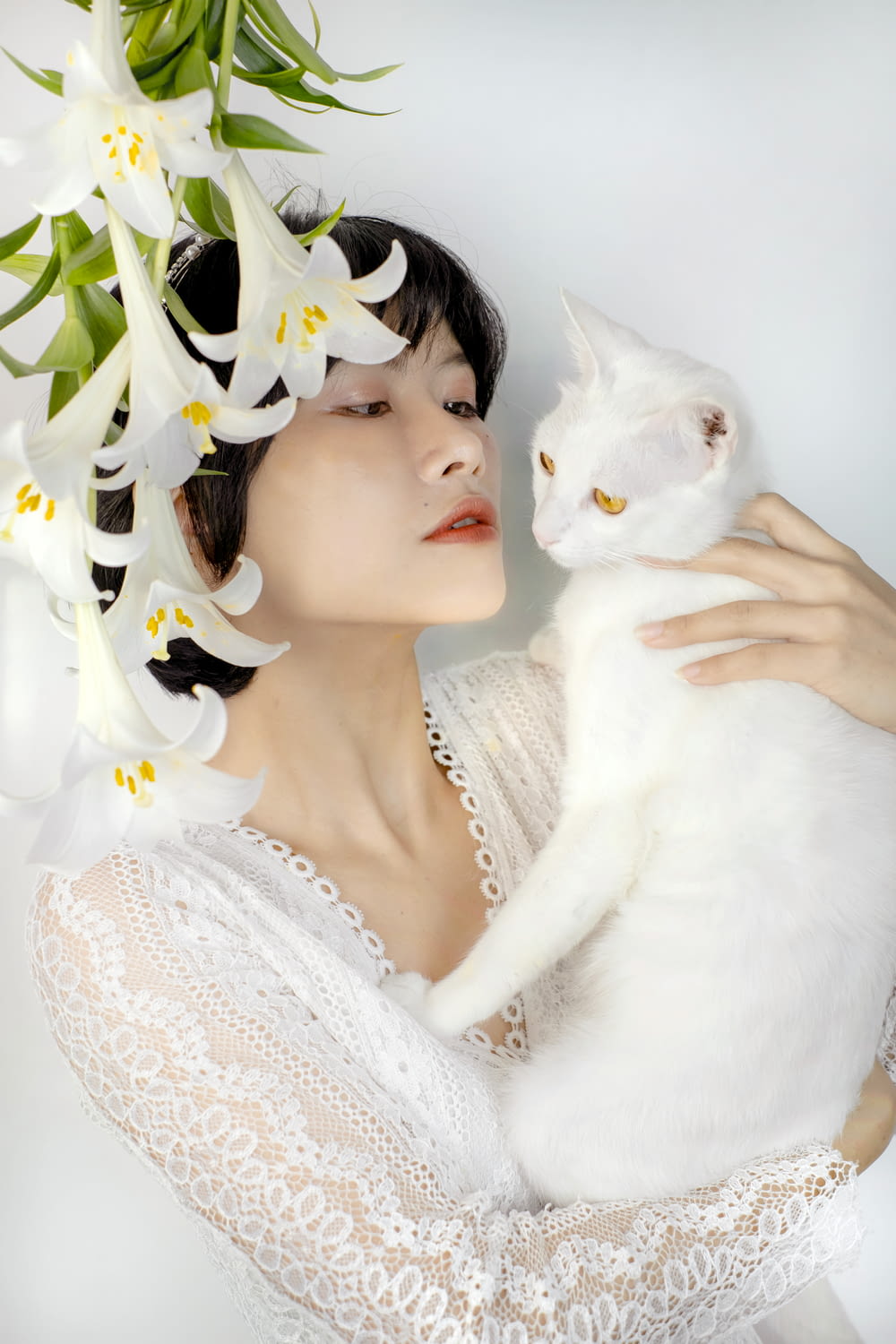 Una mujer con un vestido blanco sosteniendo un gato blanco
