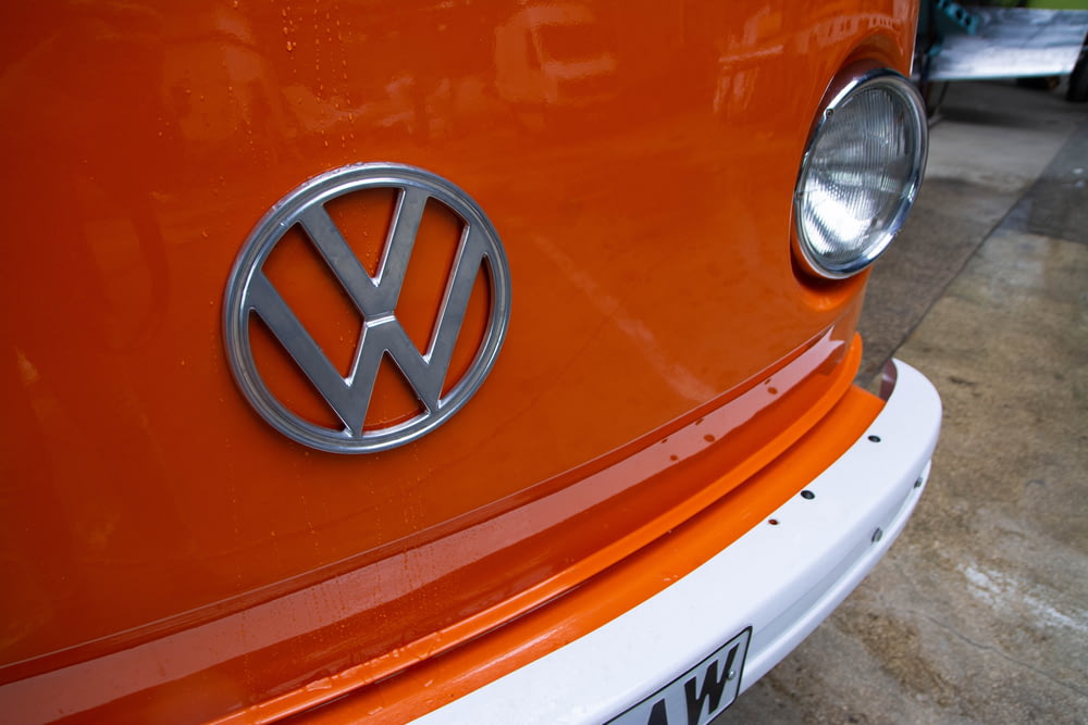 a close up of a volkswagen emblem on an orange car