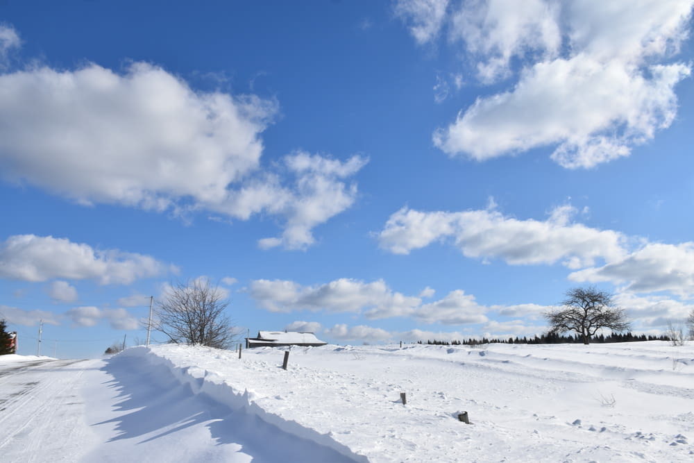 a road that is covered in snow under a cloudy blue sky