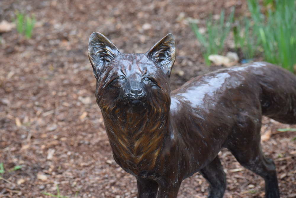 a bronze statue of a dog in a garden
