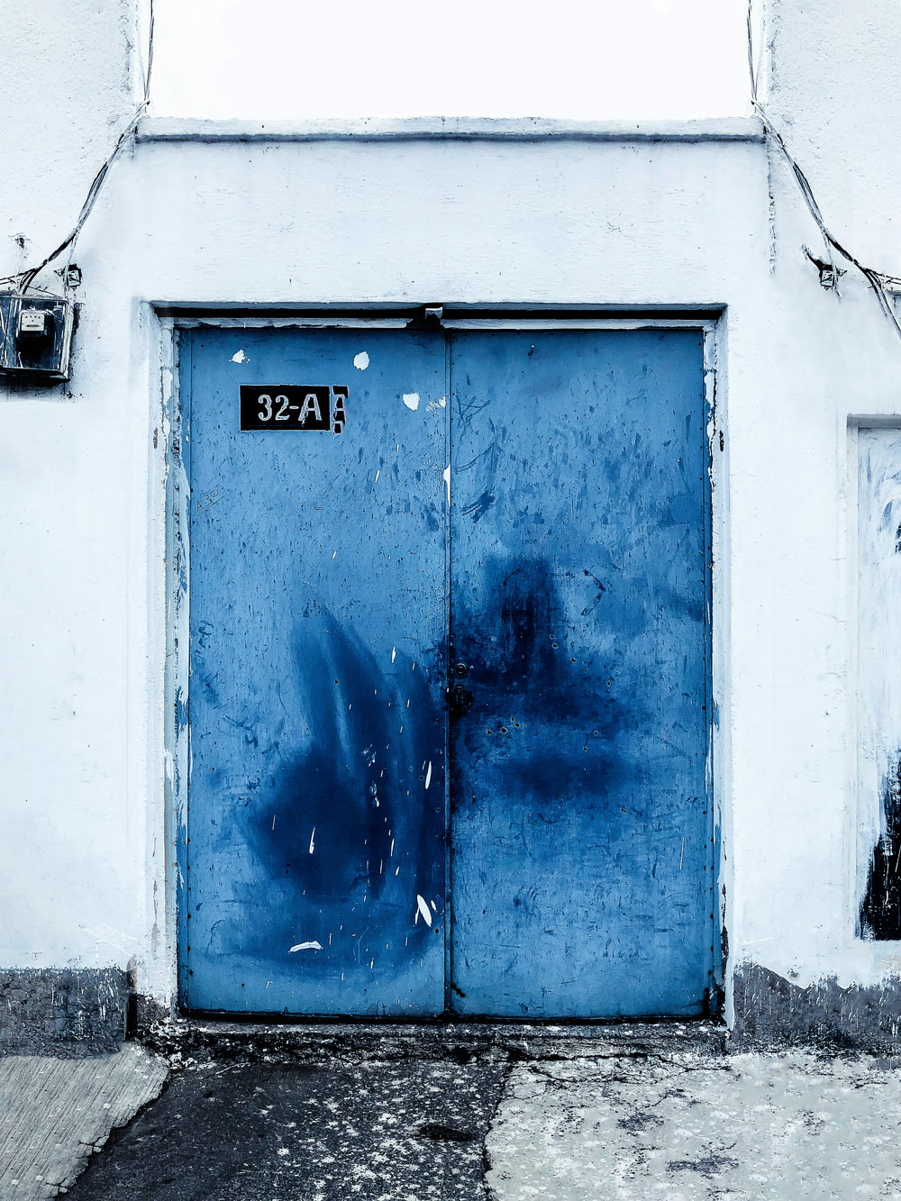 a blue door on a white building with graffiti on it