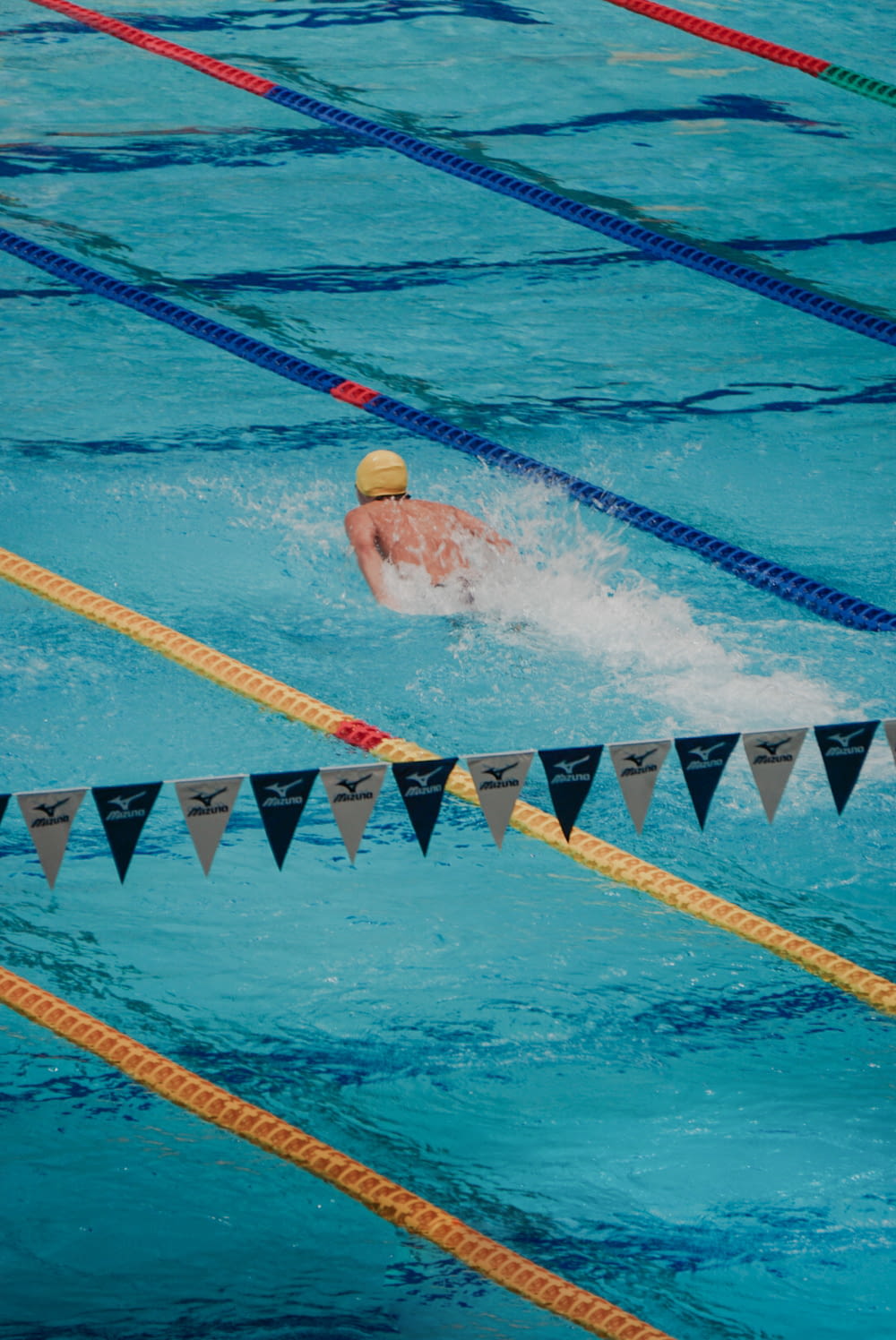 旗に囲まれたプールで泳ぐ男