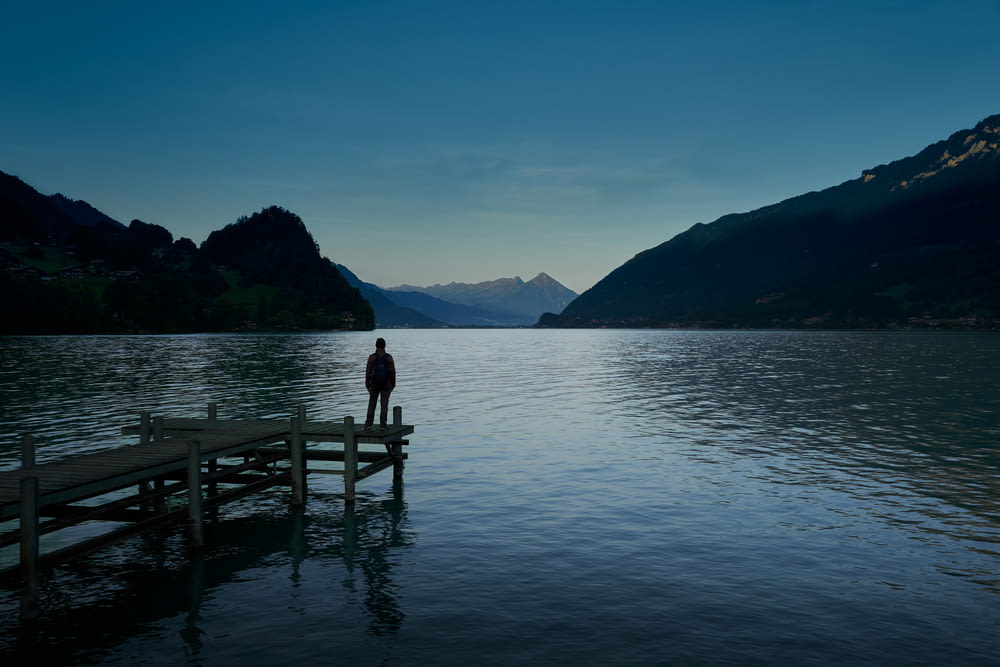 a person standing on a dock in the middle of a lake