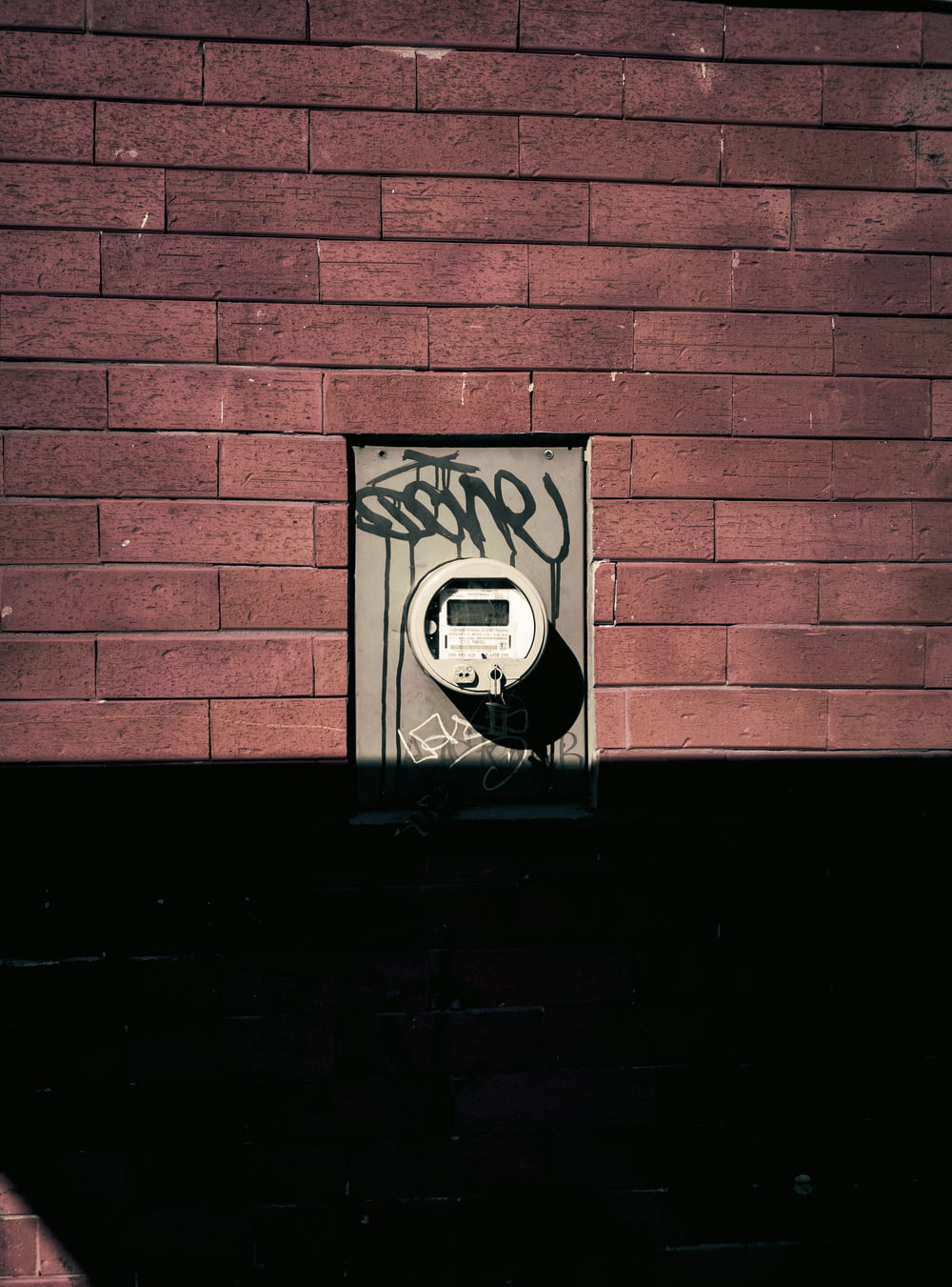 a brick wall with graffiti on it and a parking meter