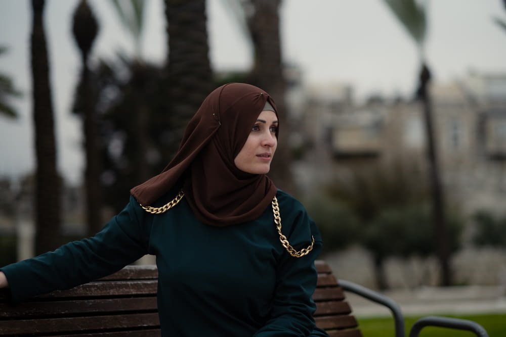 a woman in a hijab sitting on a bench