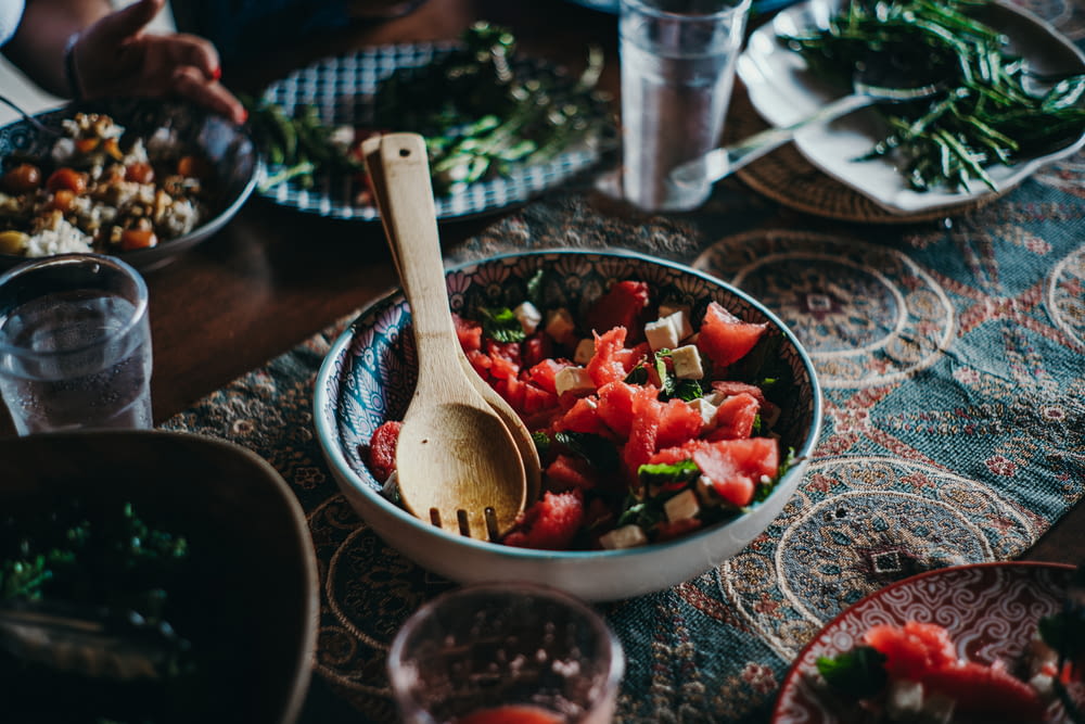 a bowl of watermelon salad with a wooden spoon