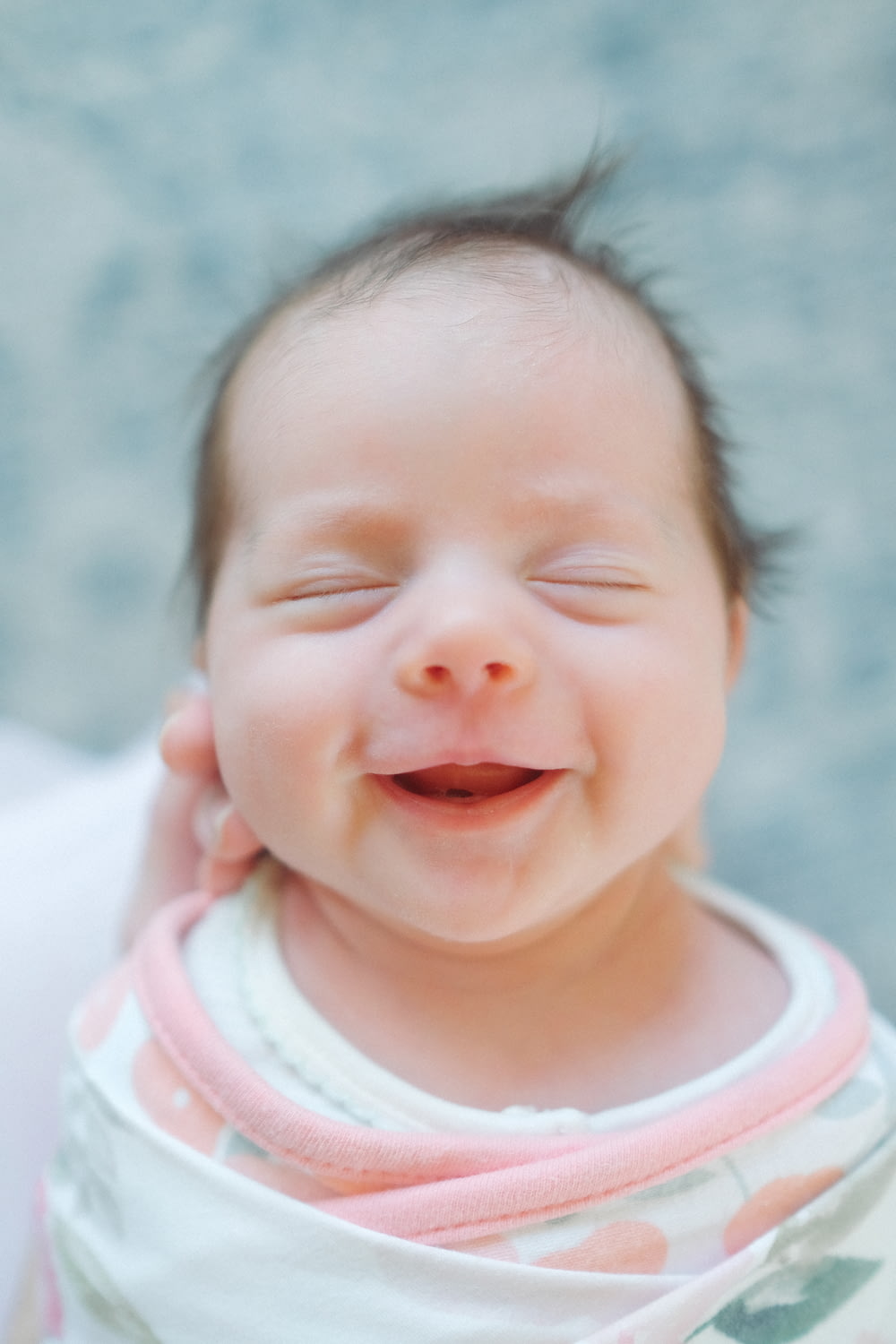 Un primer plano de un bebé sonriendo con los ojos cerrados