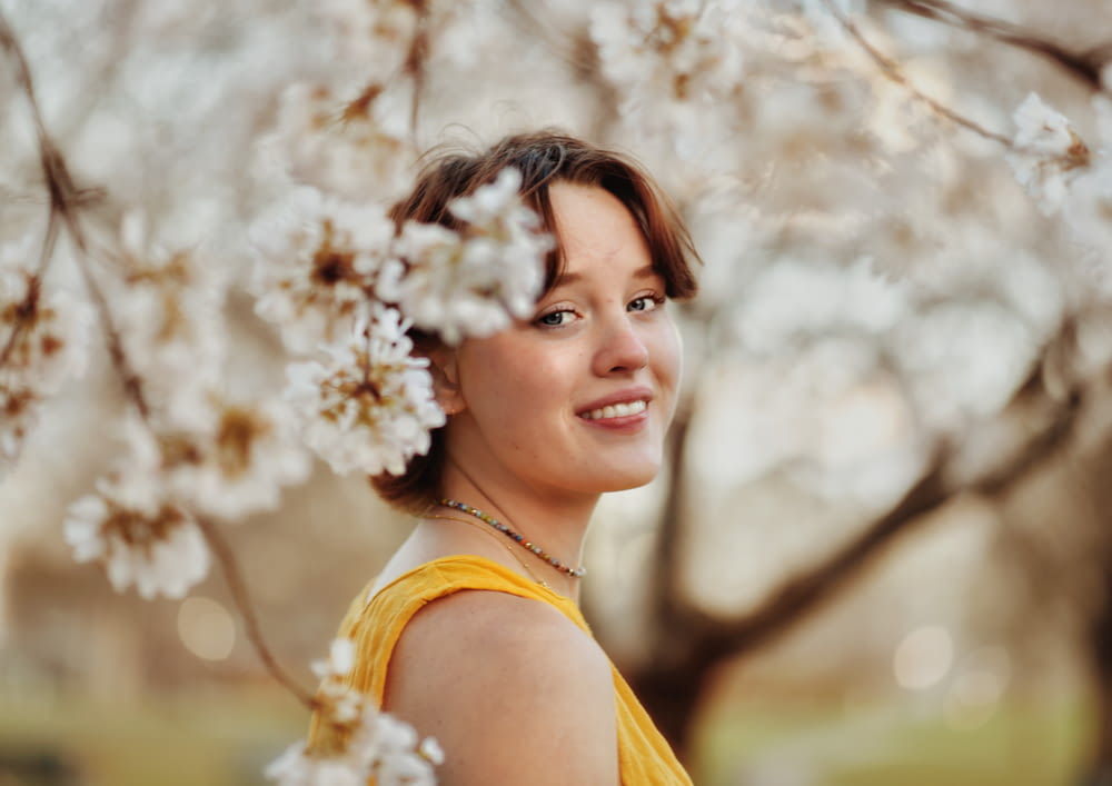 a woman standing under a tree with white flowers