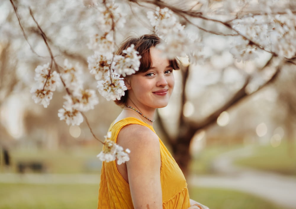 a woman in a yellow dress standing under a tree