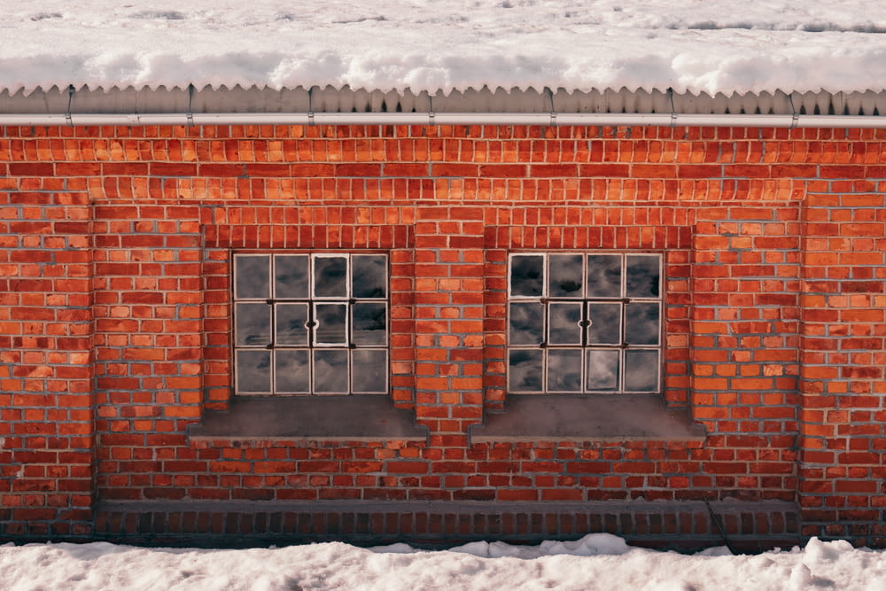 a red brick building with three windows in the snow