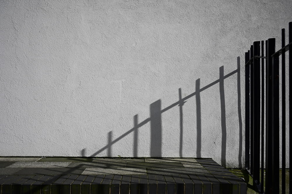 a shadow of a fence on a white wall