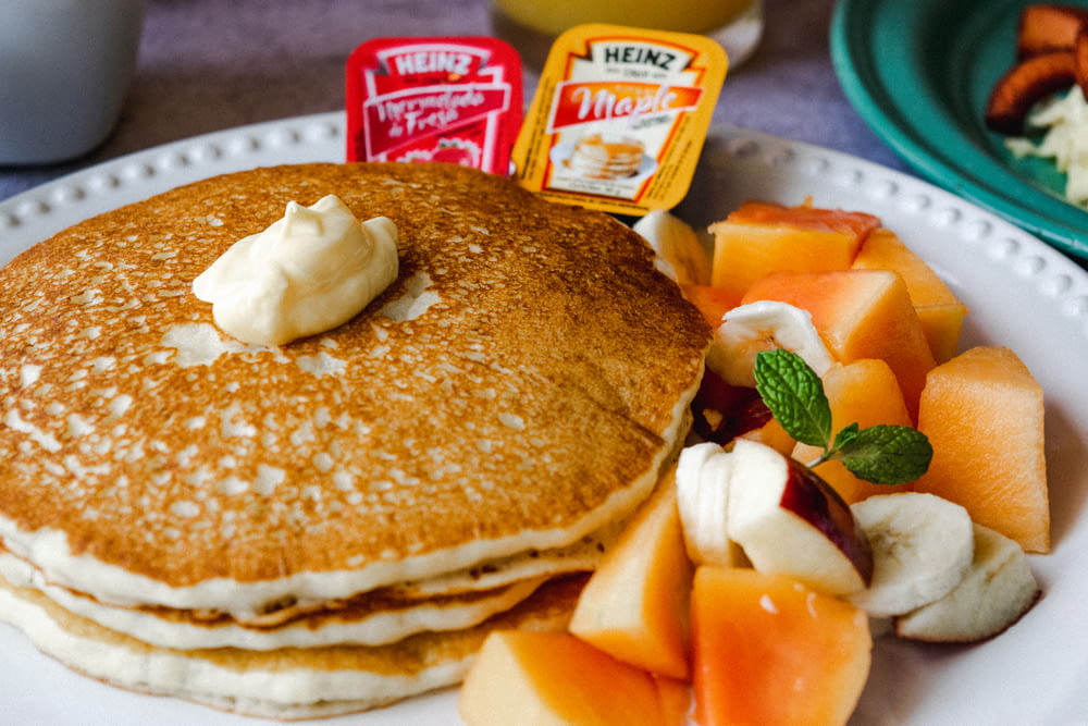 a white plate topped with pancakes and fruit