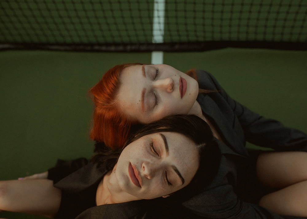 a couple of women laying next to each other on a tennis court