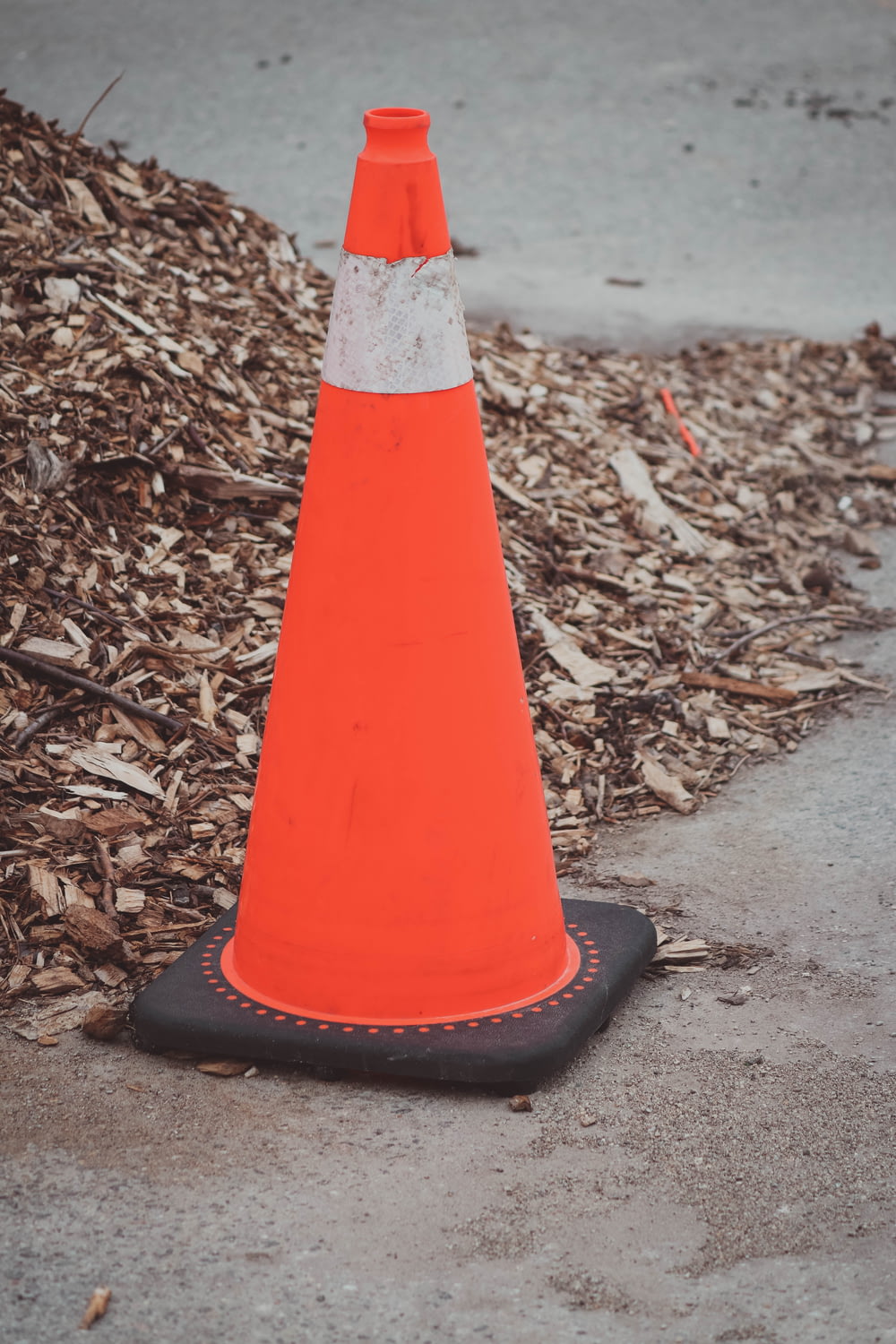 an orange traffic cone sitting on the side of a road