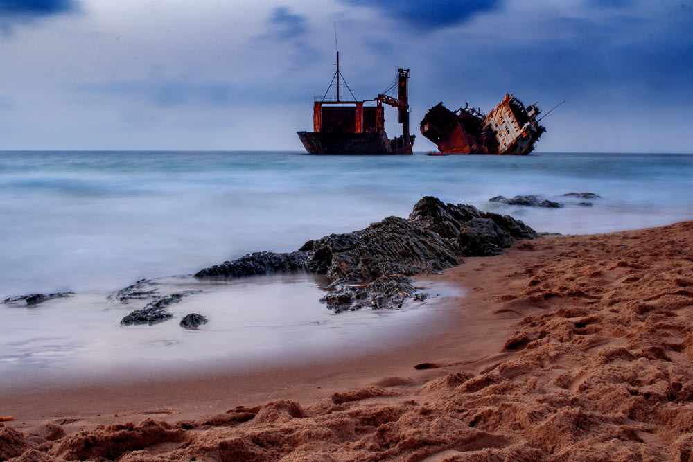 a ship sitting on top of a sandy beach next to the ocean