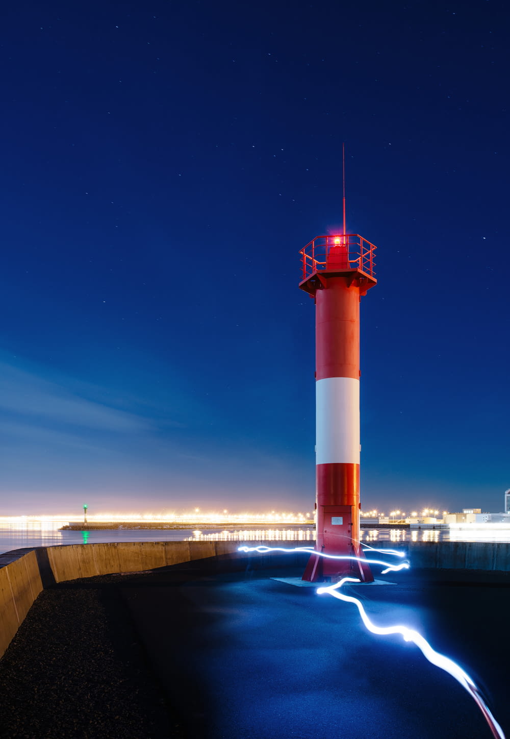 a red and white light house sitting on top of a pier