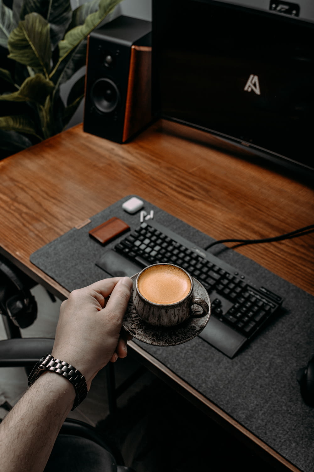 a person holding a cup of coffee in front of a computer