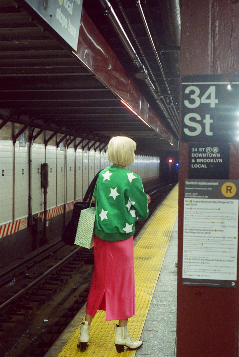 a person in a green jacket and red skirt standing on a platform