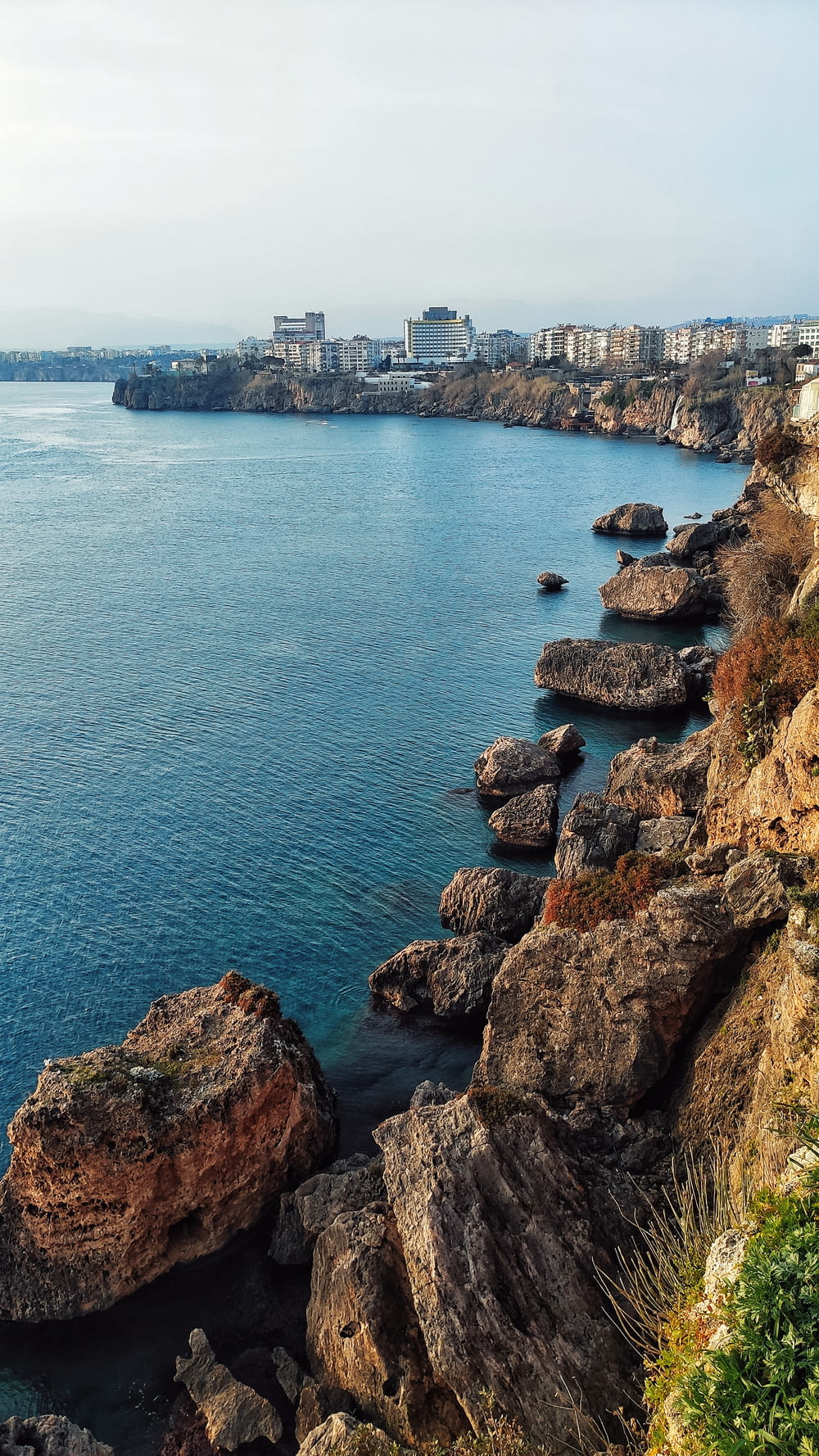 a rocky shoreline with a city in the background