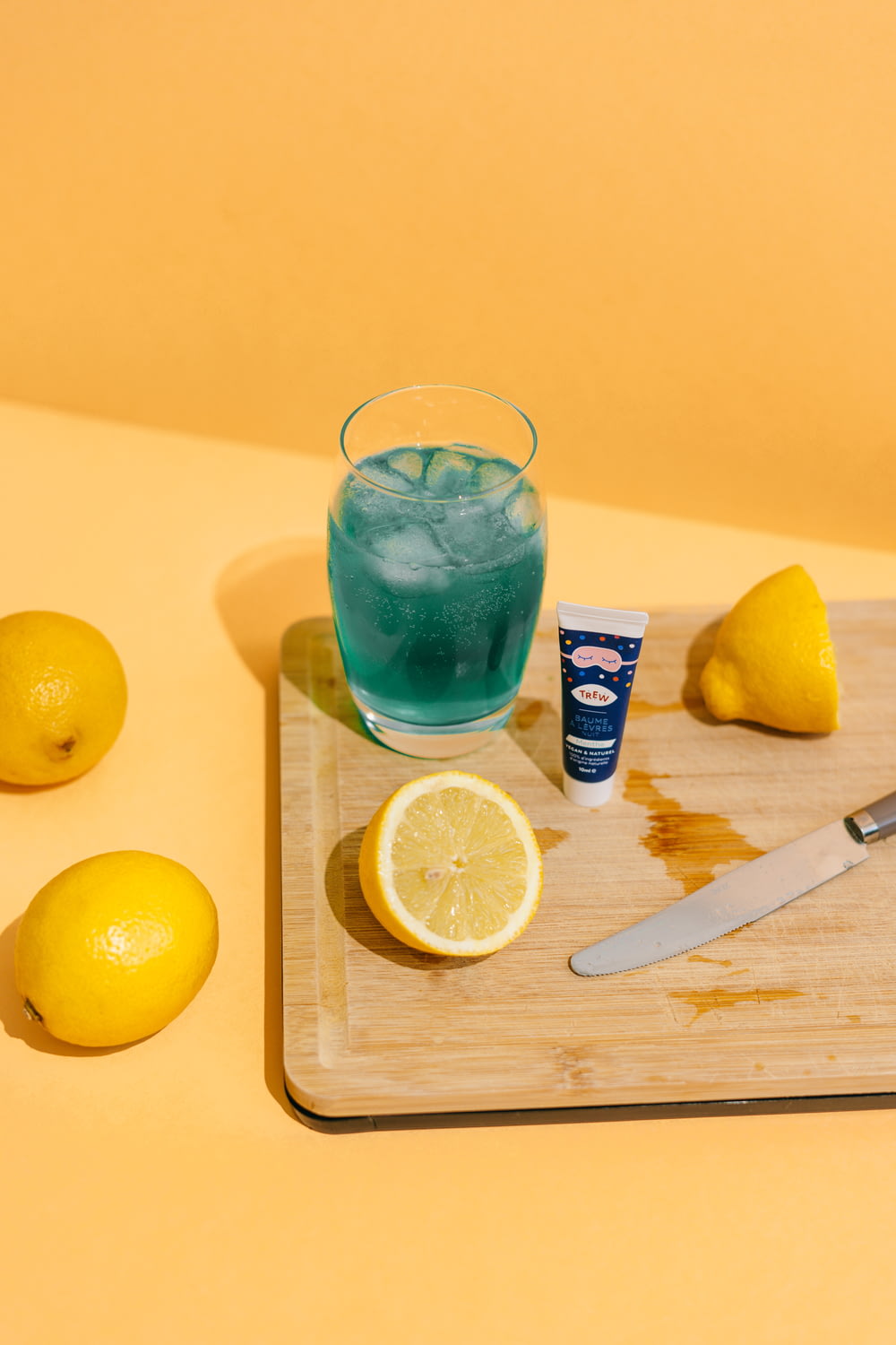 a glass of water and lemons on a cutting board