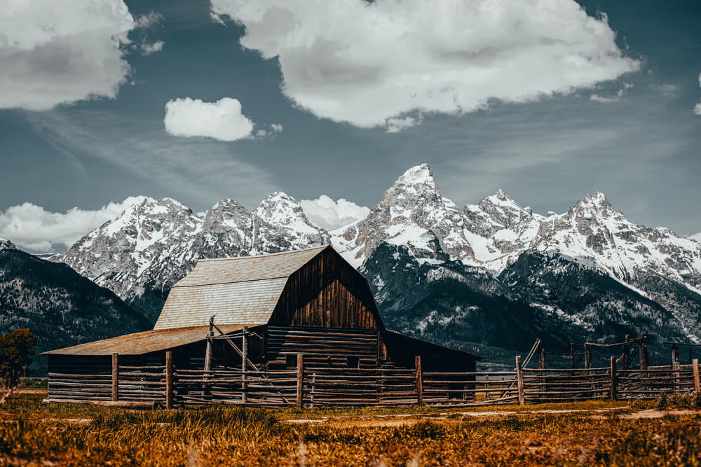a barn in front of a snowy mountain range
